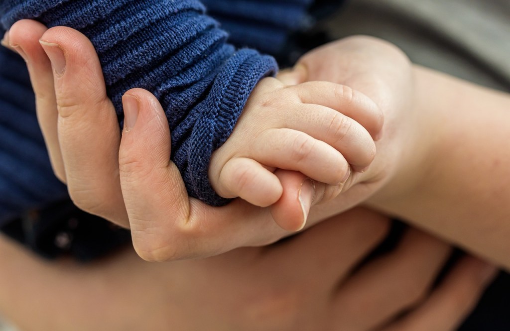 infant hand holding father's hand
